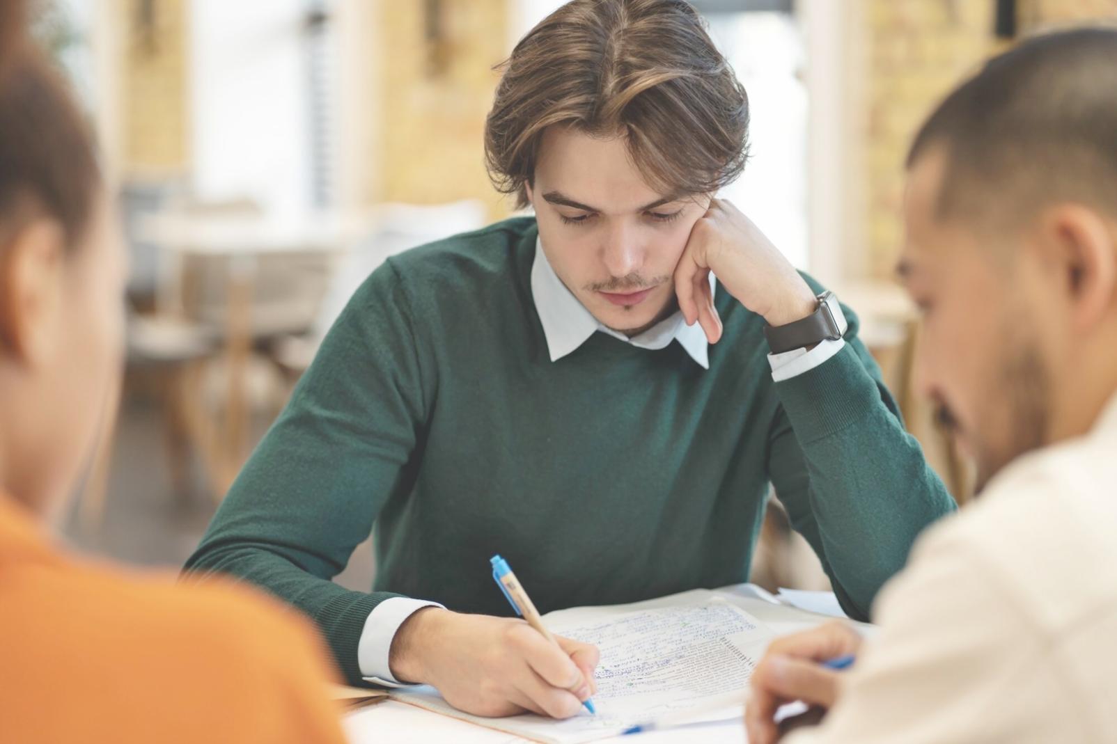 Étudiant concentré sur l'apprentissage de l'écriture japonaise avec des supports pédagogiques